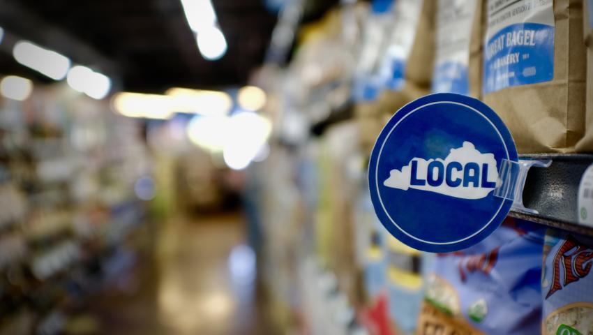 Landscape-style photo of a "Local" signage tag on a grocery store shelf